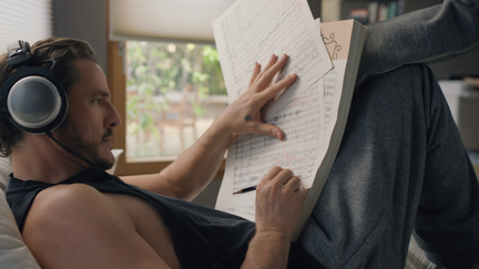 Pedro Pascal liegt auf der Couch und liest Musiknoten